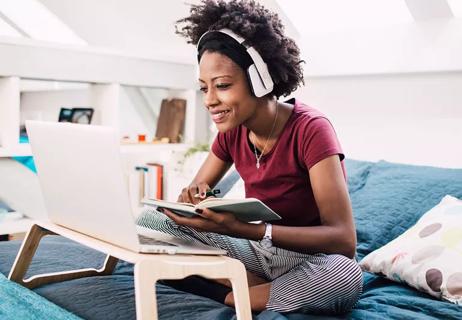 Person on laptop working from bed at home.