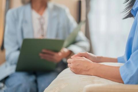 Healthcare provider holding folder, making notes, talking with patient