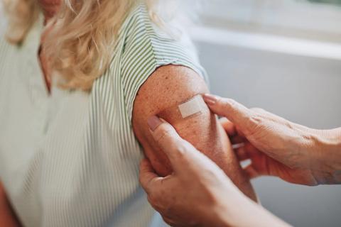 Hands putting a bandage over a vaccinated arm