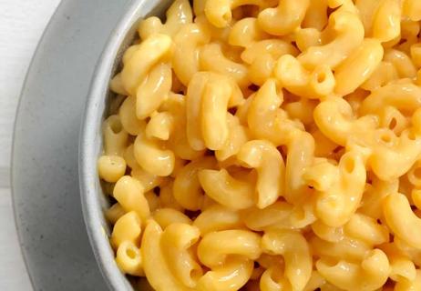 Closeup of Macaroni and cheese in a white bowl on a white background.