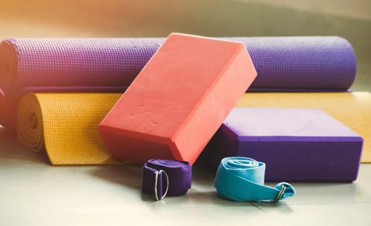 Assortment of colorful yoga props, including straps, mats and blocks