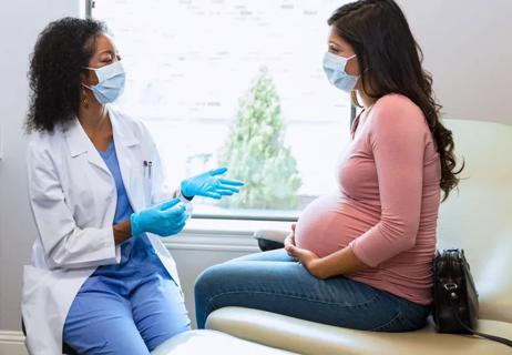 Pregnant patient visiting physician in office during exam.