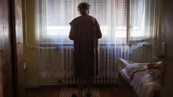 Elderly woman standing at window