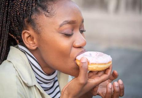 Person eating a frosted pink donut.