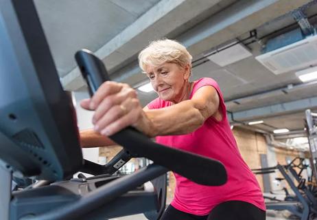 Senior woman exercising on cycling machine at rehabilitation gym