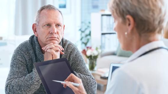 older man looking at a doctor holding an e-tablet