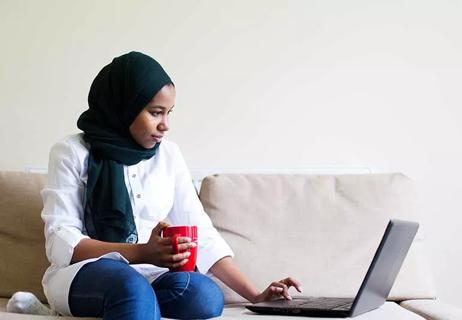 Woman sitting on a couch browsing on her laptop