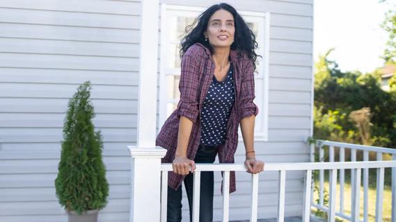 middle-aged woman leaning against porch railing