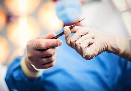 Plastic surgeon grabbing a scalpel.