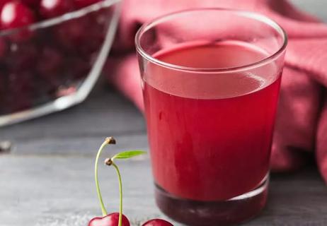 glass of cherry juice with cherries on table
