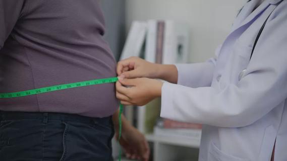 Doctor measuring patient's waist size