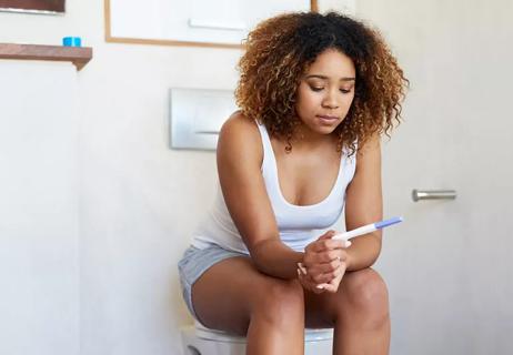 woman in bathroom holding pregnancy test