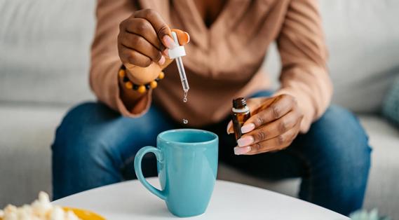Person squeezing drops of a tincture into their mug
