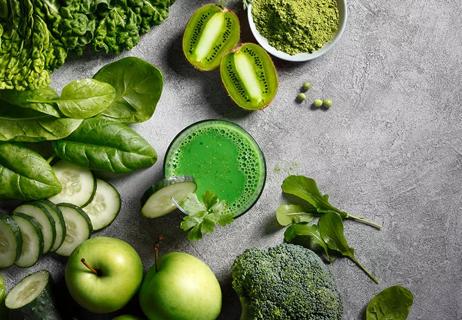 Green detox smoothie in glass,with green fruits and veggies around