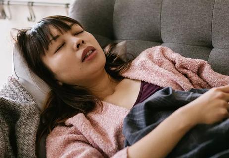 woman in discomfort lying down on couch