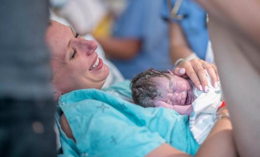 Smiling mother holding just-born baby in hospital