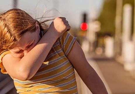 person sneezing while walking on sidewalk