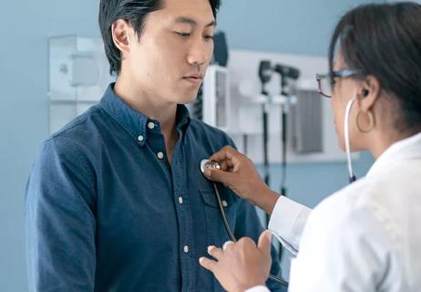 Doctor listens to patient's heart during an office appointment.