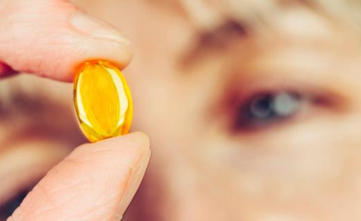 Person holding a gel capsule, examining it