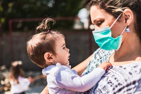 Single mother with pollution mask holding a baby