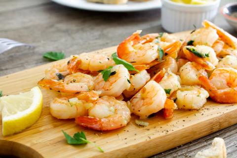 Grilled shrimp with lemon garnish on serving board
