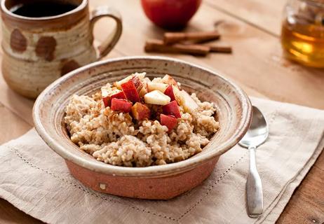 A bowl of oatmeal topped with apples