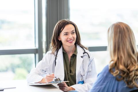 Smiling healthcare provider talking with patient at desk