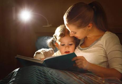 Mother reading book to daughter at bedtime