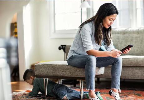 Woman sitting in living room wearing skinny jeans while son plays underfoot