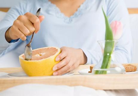 woman eating grapefruit in bed