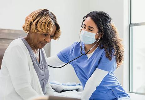 health practitioner listening to a patient's heart with a stethoscope