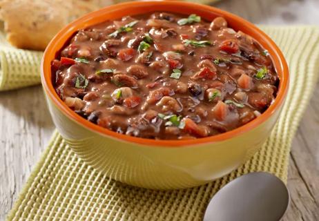 A bowl of soup with tomatoes, lentils, white beans and other veggies