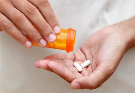 Hand pouring pills from bottle into other hand