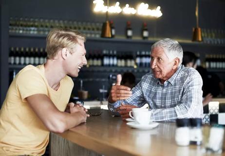 Older man and younger man talking over coffee at a cafe