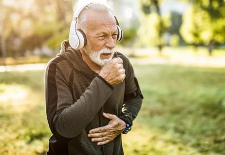 man coughing into one hand and clutching his stomach with his other hand