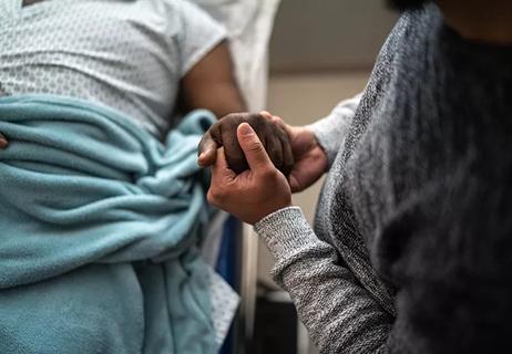 Son holding father&#8217;s hand at the hospital