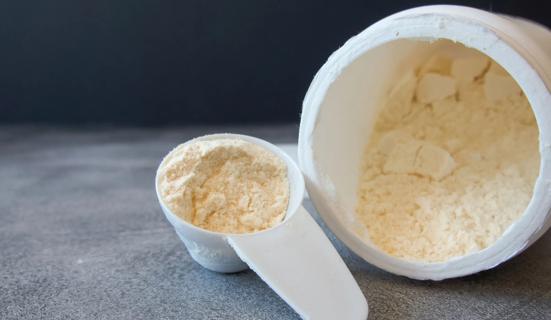 Scoop and container of bovine colostrum powder on counter