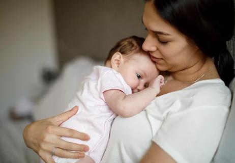 person holds small baby to their chest