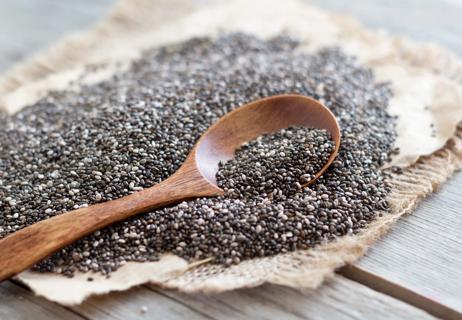 Wooden spoon of chia seeds on pile of chia seeds on piece of burlap