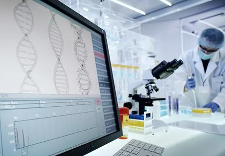 Man working on laboratory equipment. DNA research on computer screens