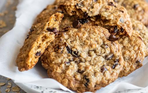 A pile of chocolate cherry oatmeal cookies sit on a napkin.