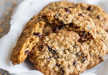A pile of chocolate cherry oatmeal cookies sit on a napkin.