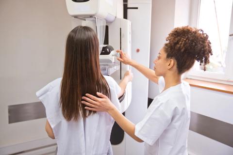 Woman receiving a mammogram, with a healthcare provider guiding