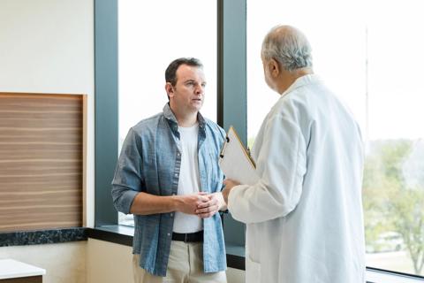 Person and healthcare provider holding clipboard standing and talking