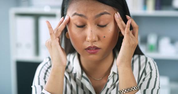 Person with eyes closed, rubbing fingers on their temples