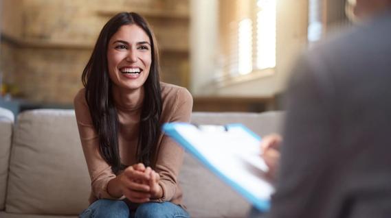 Happy, smiling female sitting across from person holding a clipboard