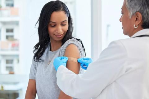 Healthcare provider apply bandaid on patient's arm after a shot