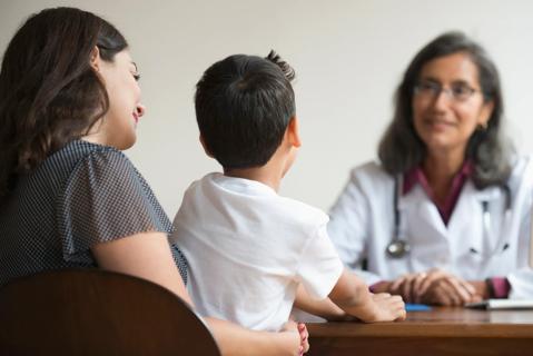 Caregiver with child on their lap, sitting across from healthcare provider, talking