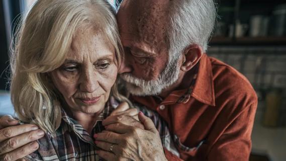 Worried older couple embracing