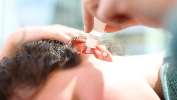 Person putting ear drops in their ear